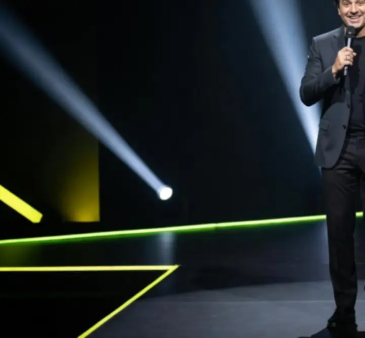 Stand-up humorista mikrofon előtt, neonfényes színpadon