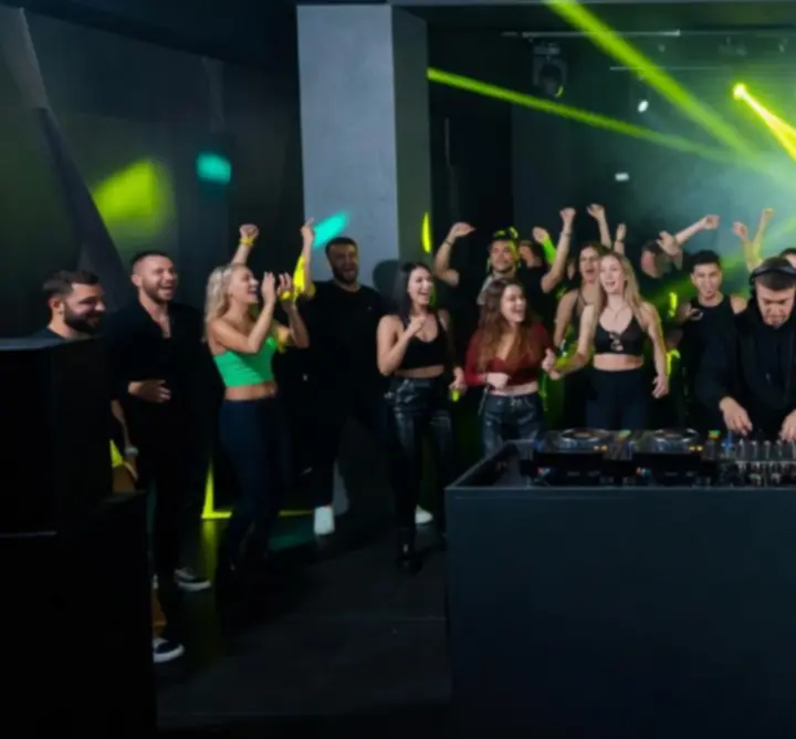 DJ pult neon-lime fényekkel és táncoló közönség éjszakai party-n